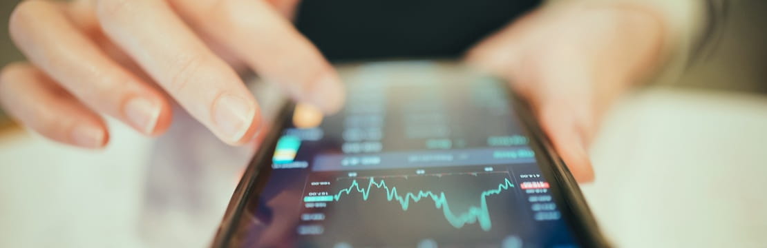 Hand using a smartphone displaying a line graph
